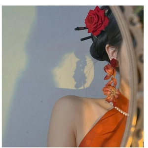 Artistic detail of red rose floral earrings with long tassels and silk flower hair pin