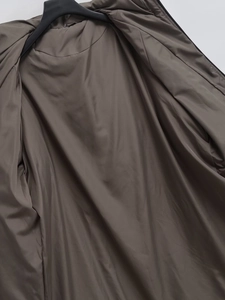 Detailed macro view of the smooth dark brown polyester lining and stitching of the long coat