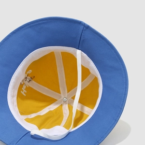 Detailed view of the yellow cotton lining and white chin strap on the dinosaur bucket hat