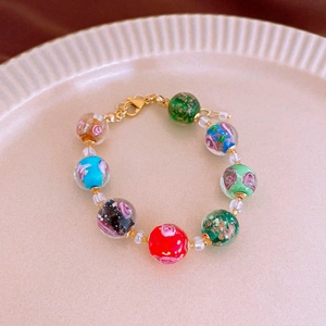 Detail of colorful glass beads bracelet with rose patterns and golden metal clasp