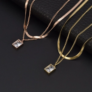 Colliers double rang en or et or rose avec pendentifs zircon carrés sur fond noir texturé