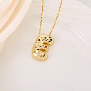 Close-up of letter E pendant with colorful cubic zirconia on golden chain necklace