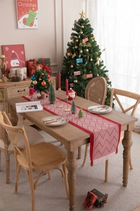 Close-up of red and white Christmas table runner with tassels and festive decor