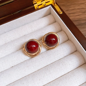 Vintage stud earrings with dark red stones and gold braided frames in a wood jewelry box