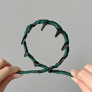 Flexible dark green fabric headband with plastic teeth shown in hand to display high elasticity