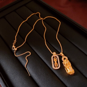 Macro shot of gold Pixiu and Vajra pendants with zircon on black leather tray