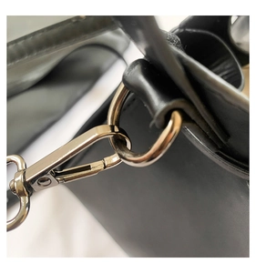 Detail of silver metal lobster clasp and black leather strap on punk triangle bag