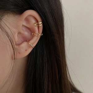 Close-up of three different minimalist gold ear cuffs on ear without piercings