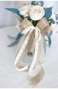 Detail of bridal bouquet handle wrapped in burlap with lace ribbon and large bow