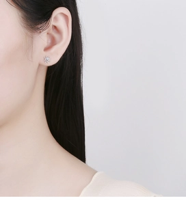 Detail of 925 sterling silver sunburst stud earrings with blue zircon on female model