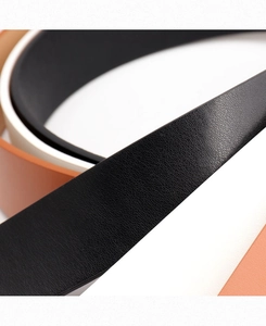 Close-up of three leather belts in black white and brown with litchi grain texture