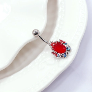 Gros plan du piercing de nombril argenté avec pierre rouge sur porcelaine blanche