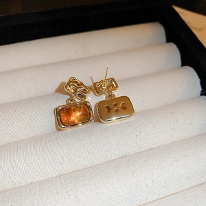 Detail of vintage amber resin earrings with irregular gold-plated hammered metal texture