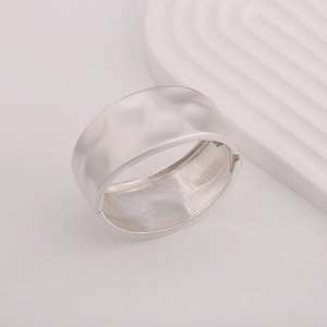 Detail of silver matte cuff bracelet with textured hammered surface and side hinge closure
