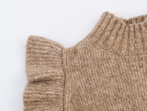 Detailed macro view of brown knit top featuring ruffle shoulder trim and ribbed texture
