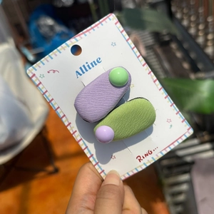 Close-up of purple and green fabric hair clips with bead accents on display card