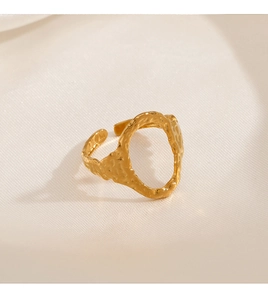Macro shot of gold adjustable ring showing hammered metal texture on beige silk