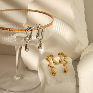 Boucles d'oreilles irrégulières fluides or et argent sur fond de pierre minimaliste
