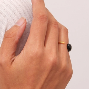 Detailed view of an open golden ring with black drop-oil accents on a model hand