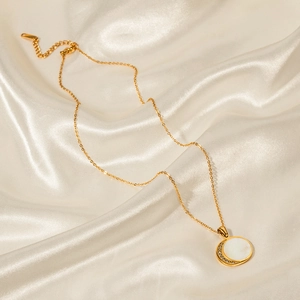 Close-up of 18K gold stainless steel necklace with sun and moon shell pendant on silk