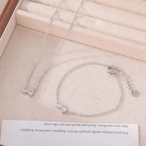 Parure collier et bracelet nœud argenté avec cristaux étincelants sur plateau de bijoux