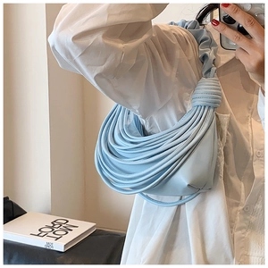 Detail of light blue knotted woven handbag featuring a unique crescent shape design