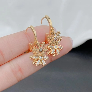 Detailed macro shot of golden snowflake earrings with embedded white zircons for Christmas