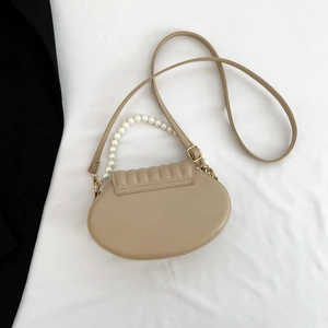 Detail of beige PU leather shell bag with pleated flap and elegant pearl handle strap