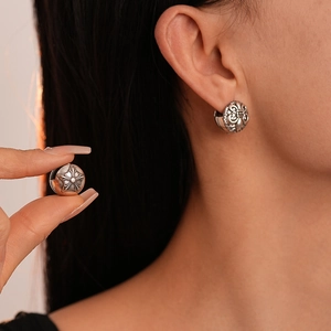 Vintage silver earrings with gothic iris and star relief patterns shown on a model