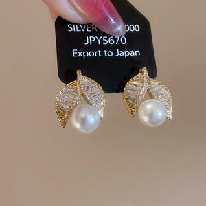 Detailed macro view of leaf shaped earrings with zircons and white round pearls