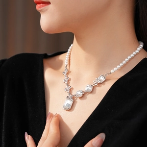 Close-up of pearl beaded necklace with square crystal pendant worn by a model