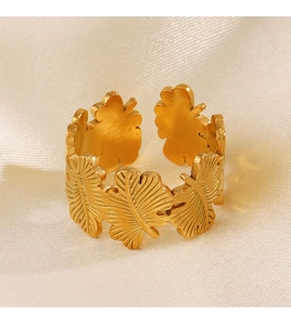 Detailed macro view of golden leaf pattern adjustable ring on white silk background
