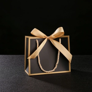 Detail of luxury black gift bag with gold trim, ribbon bow, and rope handles