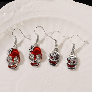Detail of gothic skull earrings with red drip oil and red crystals in white tray