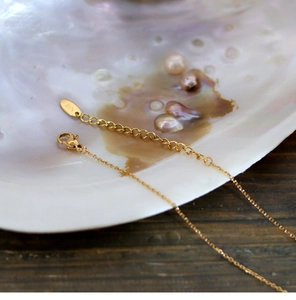 Detailed macro view of 18K gold adjustable necklace clasp with K18 engraved metal tag