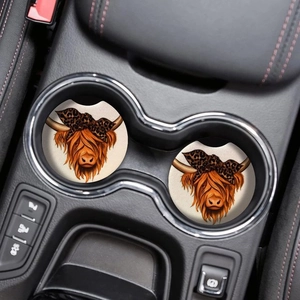 Close-up of highland cow absorbent coasters placed inside a car cup holder