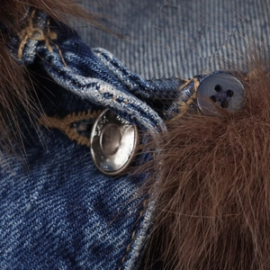 Detailed macro shot of blue denim jacket with brown faux fur collar and silver metal button