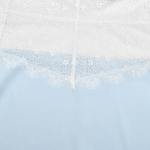 Close-up detail of white floral lace texture on light blue fabric for the halter dress