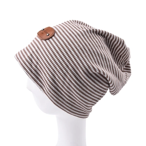 Detail of striped knit beanie with brown leather logo patch on soft textured fabric