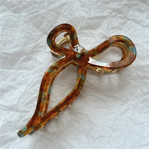 Detail of premium acetate claw clip featuring amber tortoiseshell pattern with blue accents