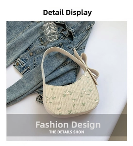 Detail of floral embroidery and a large white bow on a woven straw underarm bag