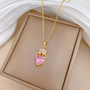 Detail of crown heart pendant necklace with pink crystal on white silk fabric