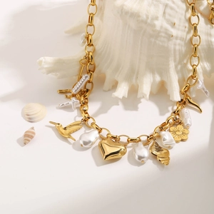 Collier en acier doré avec pendentifs cœur et perles baroques sur un coquillage