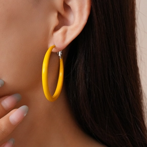 Close-up of model wearing bright yellow geometric round hoop earrings with a matte finish