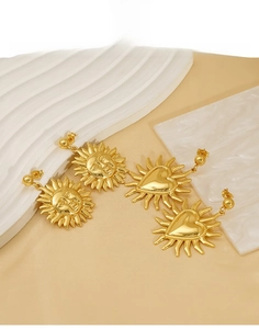 Detailed macro view of retro 18K gold-plated titanium steel sun face and heart earrings