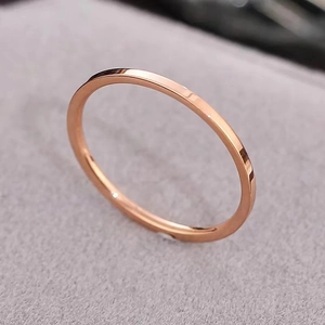 Anillo minimalista de acero de titanio oro rosa sobre fondo de terciopelo gris