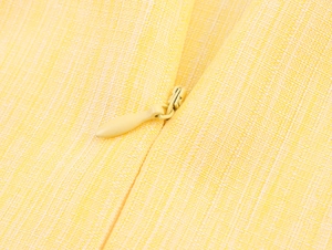Detailed macro view of yellow linen-textured fabric and a matching invisible zipper