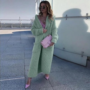 Outdoor street style of a long mint green chunky knit cardigan paired with a pink silk camisole