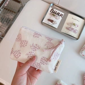 Close-up of small floral cotton coin purse with bow patterns and side brand tag