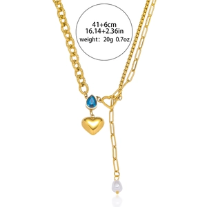 Gold heart necklace with blue teardrop gemstone and pearl tassels on a mixed chain